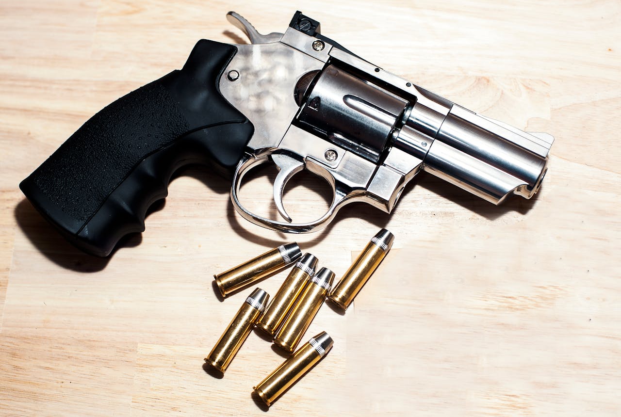 digital Silver revolver and bullets on a wooden surface illustrating security themes.
