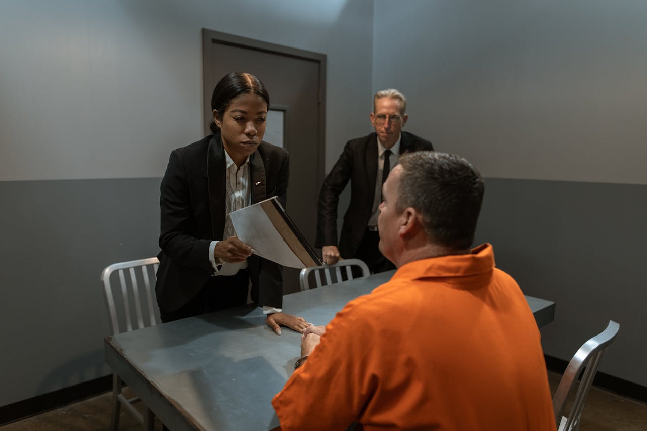 brand-02 A tense interrogation scene in a prison room with officials and a prisoner.