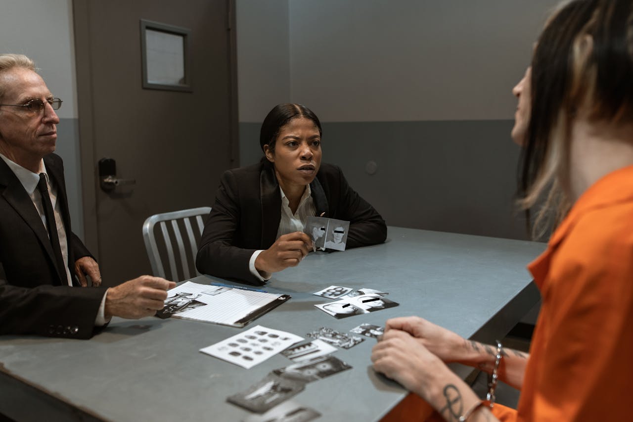 Services-01 Interrogation scene with detectives questioning a handcuffed suspect inside a jail room.
