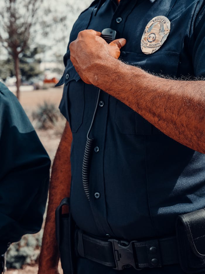 brand-01 A close-up image of a police officer adjusting a radio outdoors.