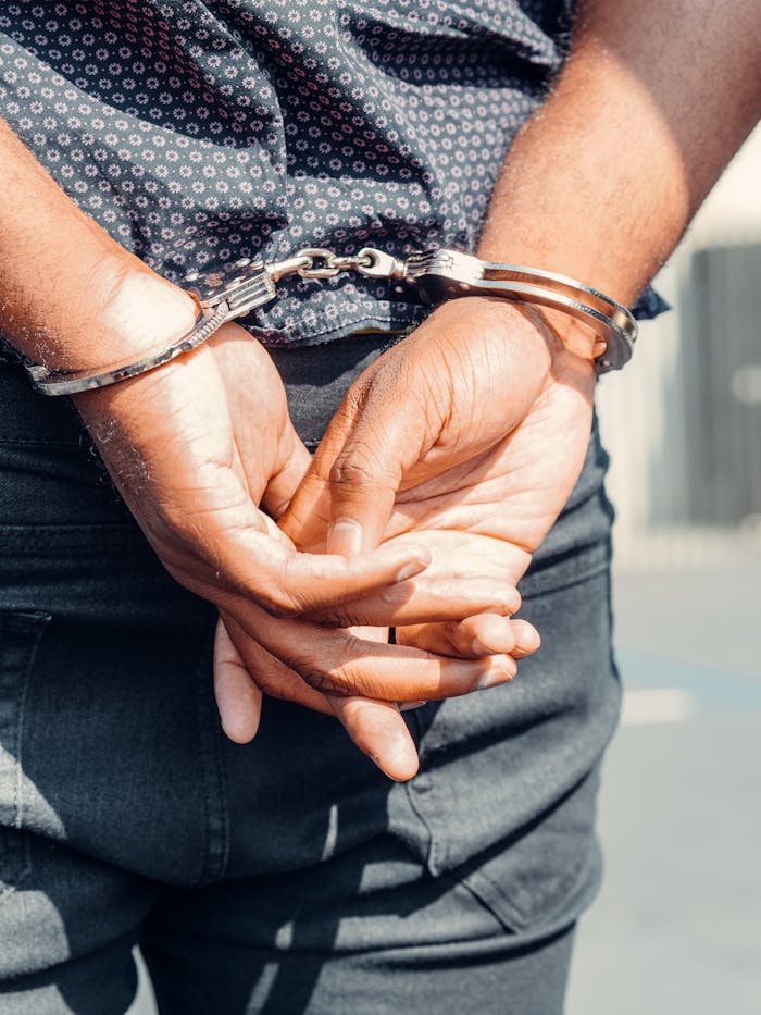 Services-02 Rear view of a person in handcuffs outdoors, symbolizing law enforcement and justice.